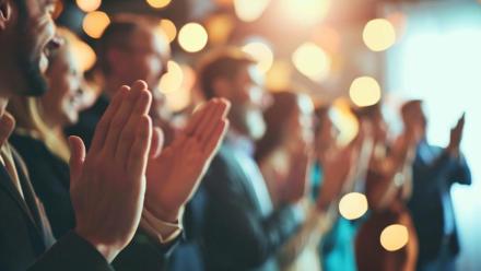 Colleagues giving a standing ovation to an awarded team member,