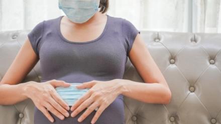 A pregnant woman wears a surgical mask to protect a COVID-19 (Coronavirus) and PM 2.5 and show a surgical mask on the abdomen to prevent infection to the fetus.
