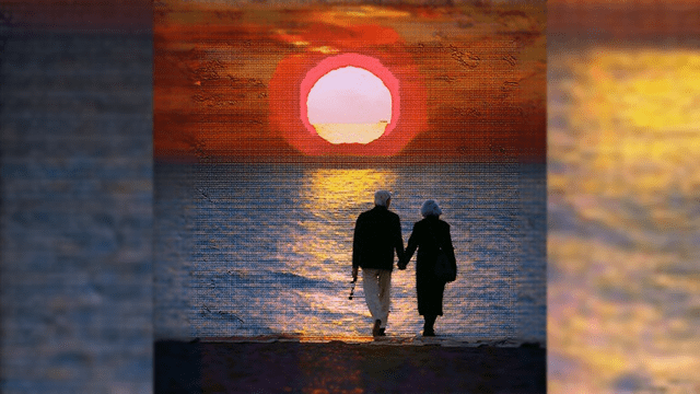 Elderly couple walking on the beach towards the sunset